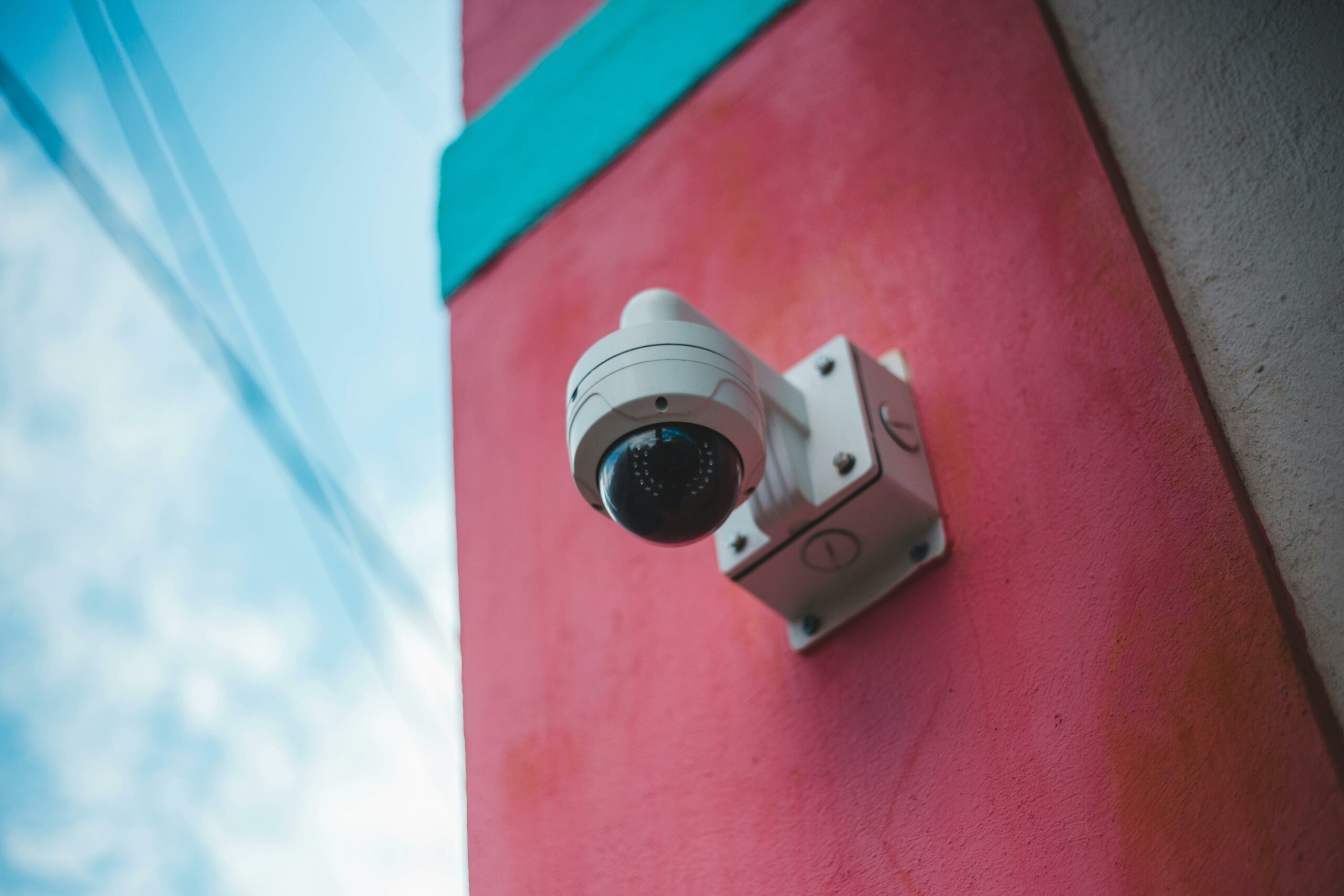 Caméra dôme de vidéosurveillance fixée sur une façade extérieure rose