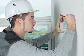 Technicien installant un système de sécurité sur un mur avec un clavier numérique, installation d'alarme