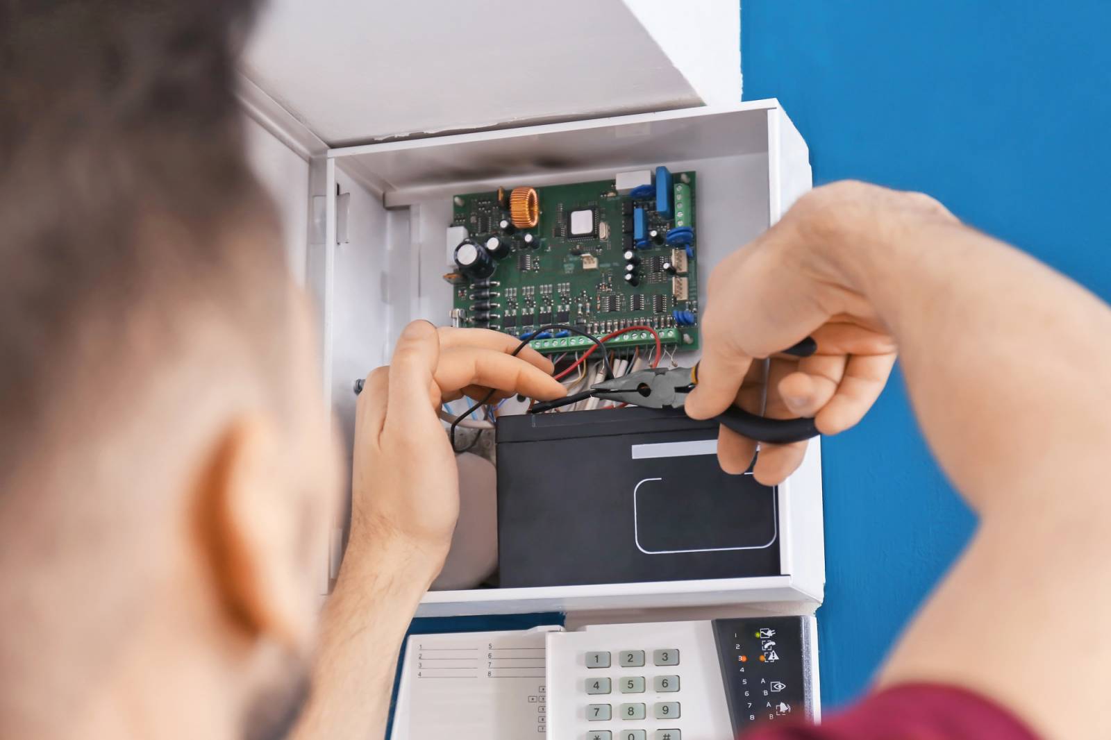 un technicien d'alarme réalise une maintenance sur une centrale intrusion